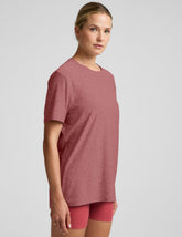 model wearing an oversized men's red t-shirt and shorts on a plain background.